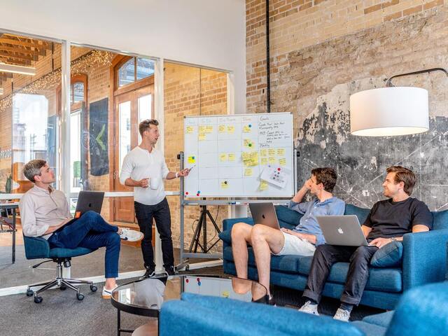 Man presenting to small team in trendy office workspace.