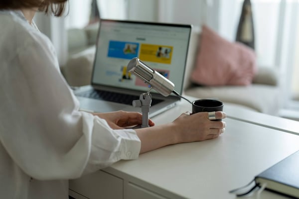 Woman with microphone presenting on laptop screen.