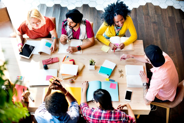 Top view photo of seven employees discussing business objectives at a table