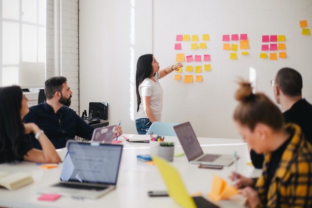 Group of employees with woman at whiteboard.