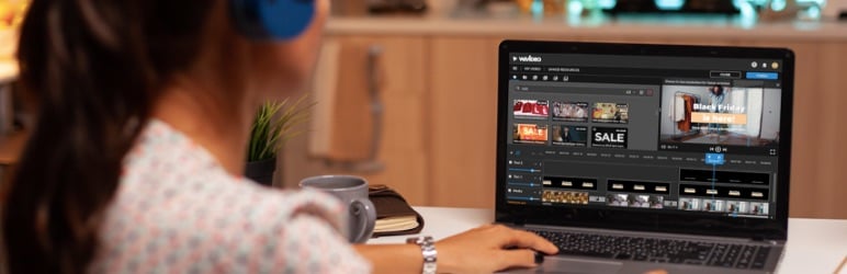 Woman using a laptop to edit video while wearing headphones